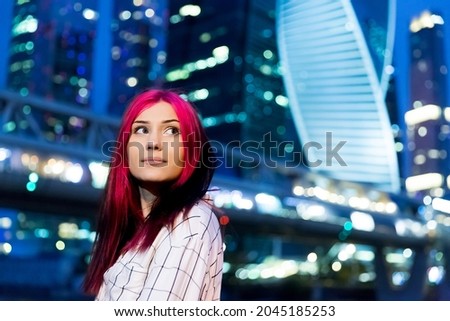 Close up portrait of beautiful red-haired girl in the evening on lighted city street.