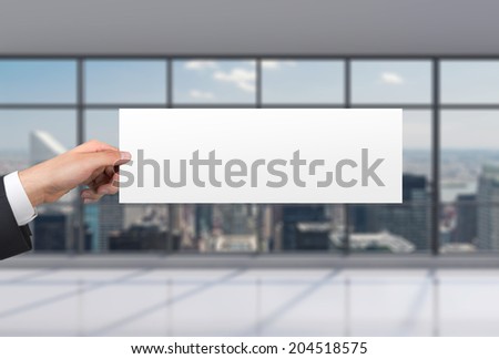 A hand is holding a blank poster in a space of a modern international consulting company. 