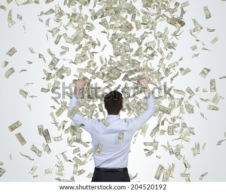 Businessman is happy about money rain as a metaphor of a successful job performance and enormous bonus payment