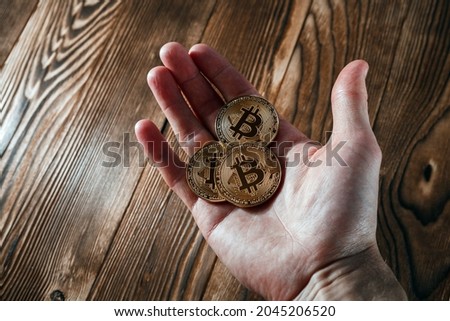 man holding bitcoin coin in hand on wood background