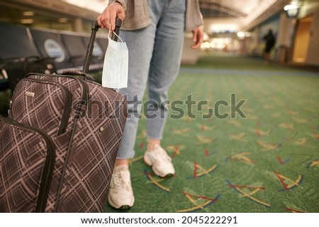 Travel during quarantine. A woman stands in the station building with a suitcase and a face mask in her hand. There is no one around. Pandemic, travel, quarantine, cornavirus, social distance. Royalty-Free Stock Photo #2045222291