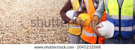 Engineers or construction industry workers stand in a row holding helmets. Concept of infrastructure development, construction and work safety. Royalty-Free Stock Photo #2045232068