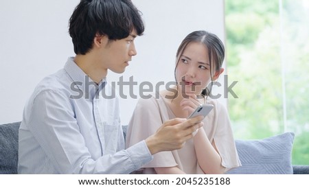 Asian young couple looking at a smartphone Royalty-Free Stock Photo #2045235188