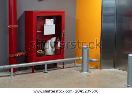 Red tube pipe system under ceiling in a parking lot , Pipe system hanging on ceiling. Installed Fire Extinguisher on the Wall of the Parking Lot