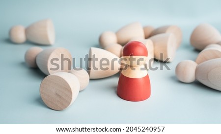 A  red wooden figure standing with other person figure lie on floor, Concept of leadership, successful competition winner and Leader with influence and winner among the losers.