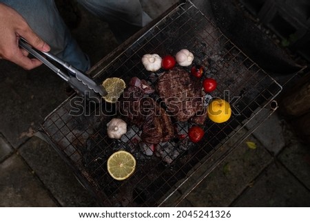 Garlic,tomatoes and meat on the grill on hot coals with smoke.