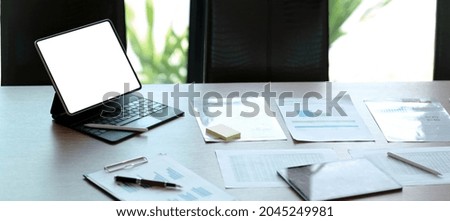 Laptop with blank screen and smartphone on table.
