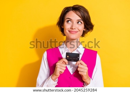 Photo of cute dreamy young woman dressed pink suit holding credit card looking empty space isolated yellow color background