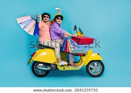 Full size photo of grey haired couple retired pensioner husband wife helmet mall debit card customer ride isolated on blue color background Royalty-Free Stock Photo #2045259710