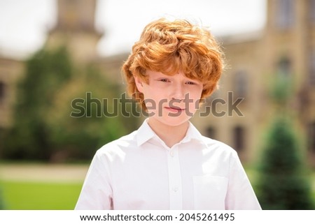 Photo of ginger redhead confident schoolboy focused look camera wear white shirt uniform park outside