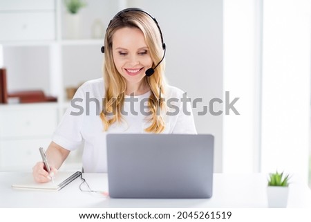 Photo of young attractive woman happy positive smile headphones speak consultant talk write notes browse laptop indoors