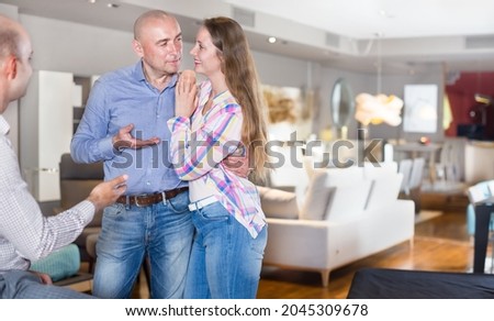 Salesman offering the furniture variants to family couple in the salon