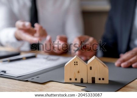Discussion With A Real Estate Agent, a businesswoman signing a contract for Insurance protecting house, a real estate home is pointing to insurance contract signing and are explaining to customers. 