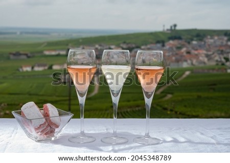 Tasting of white and rose brut champagne wine outdoor with view on green pinot noir grand cru vineyards of famous champagne houses in Montagne de Reims near Verzenay, Champagne, France