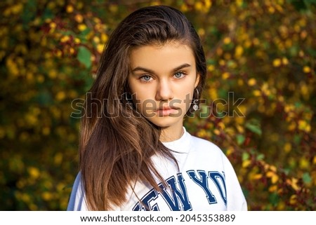 Portrait of a young beautiful brunette girl, autumn park outdoors