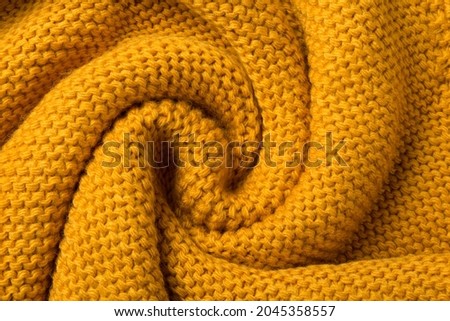 yellow knitted fabric twisted like a snail shell textured background, flat lay