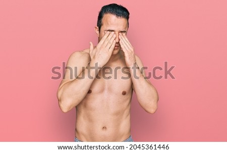 Handsome young man wearing swimwear shirtless rubbing eyes for fatigue and headache, sleepy and tired expression. vision problem 