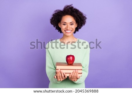 Photo of young cheerful happy afro american woman hold hands books pile apple isolated on purple color background
