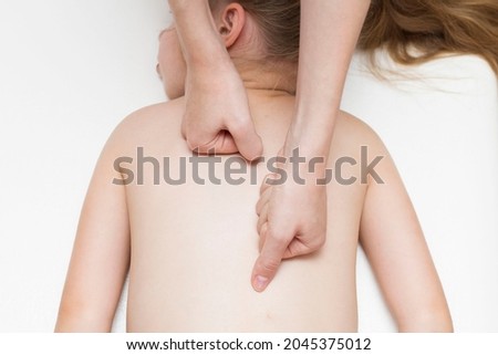 The hands of the masseur do a back massage for a girl of primary age. Spine. Back pain in school-age children.