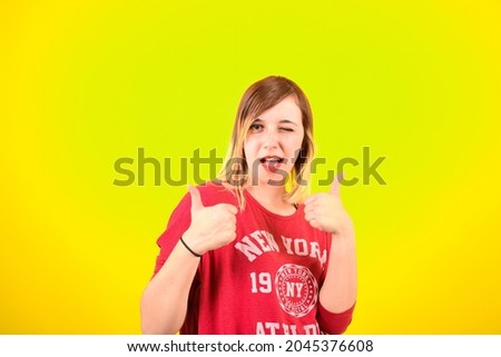 Cheerful woman with thumbs up successfully approving something on isolated yellow background