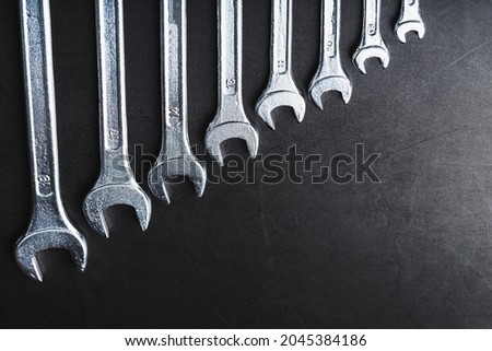 A set of wrenches on a textured black background in a row. Top view, free space