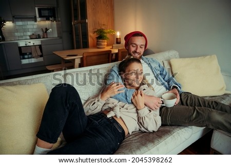 Caucasian couple cuddling on couch hugging each other and smiling  Royalty-Free Stock Photo #2045398262