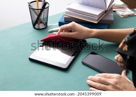 Woman sitting at the office table and wiping pc tablet and smartphone screens.Empty space
