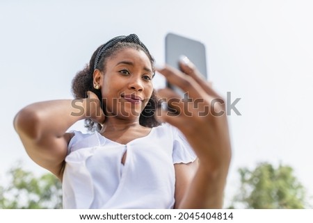 beautiful young African American woman taking a selfie in the park