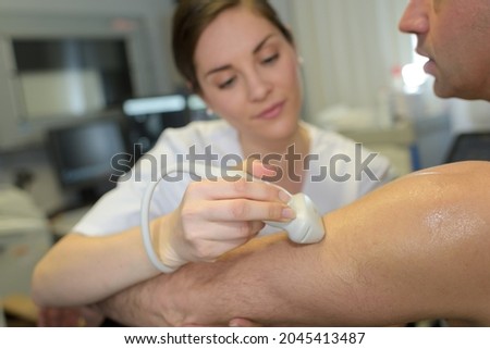 female doctor with male patient undergoing arm echography Royalty-Free Stock Photo #2045413487