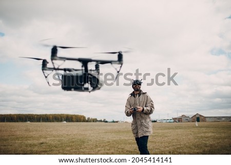 Man controlling fpv quadcopter drone for aerial photography and videography with goggles antenna remote controller. Royalty-Free Stock Photo #2045414141