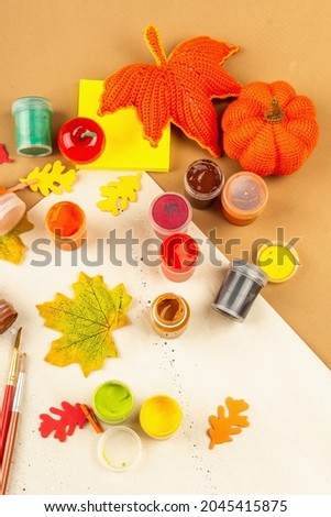 Creative autumn colors composition. Gouache, brushes, paper, traditional decor. Art, good mood, hobby, or lifestyle. Light beige background, flat lay, top view