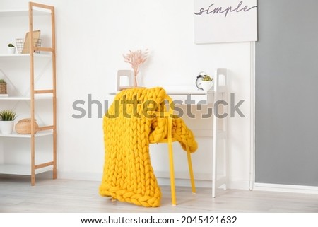 Interior of modern room with table, chair and knitted plaid