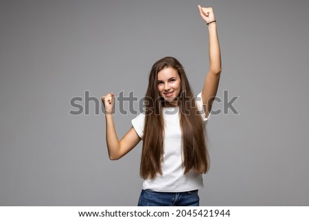 Used to success. Happy young woman in casual wear gesturing and keeping eyes closed while standing against grey background