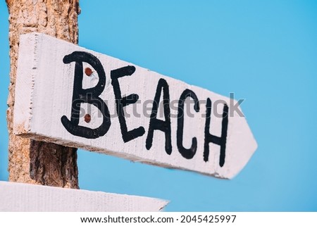 Arrow wooden direction sign painted by white color for path to the beach and sea.