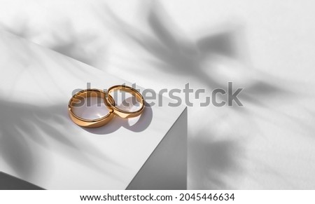 Wedding rings on a wooden box with shadows of leaves Royalty-Free Stock Photo #2045446634