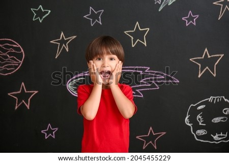 Cute little boy near black wall with drawn space