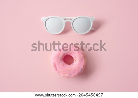 white glasses and pink donuts placed on a pink background