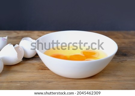 raw chicken eggs in a white cup on the table, broken shells, the concept of cooking scrambled eggs, omelet, home cooking