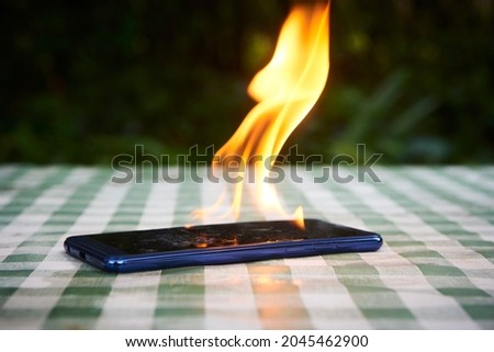 Mobile phone explodes and burns. Cell Phone explosion and fire. Smart Phone Danger from over use or bad manufacturing. Burning up overheating Smart phone concept.
 Royalty-Free Stock Photo #2045462900