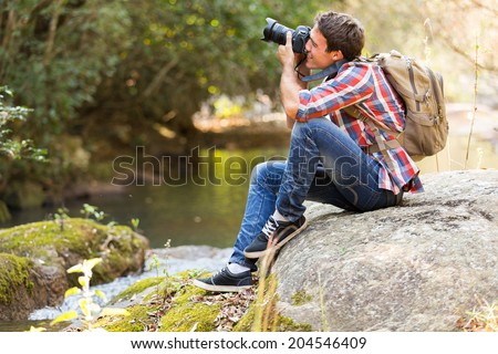 young photographer photographing in mountain valley