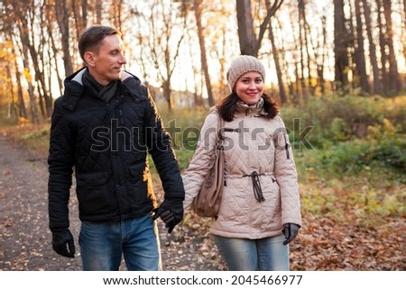 Portrait of   woman and   man on   walk in   autumn forest.
