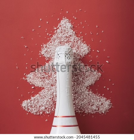 Festive red Christmas greeting card background with bottle of champagne or bubbly surrounded by a Xmas tree shaped frame of white winter snow