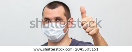 banner of man in medical mask on his face showing thumb up. Protection against contagious disease, coronavirus, flu, 2019-nCoV indoor on white background