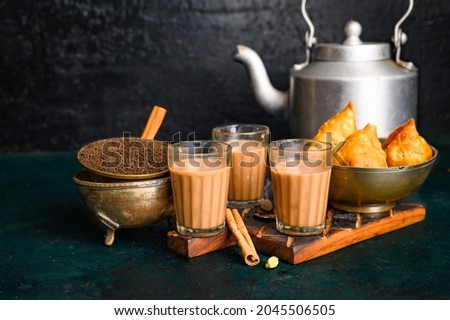 Indian masala chai spice tea with kettle, samosa and spices on dark  background. cafe, bar, restaurant, hotel concepts. Royalty-Free Stock Photo #2045506505