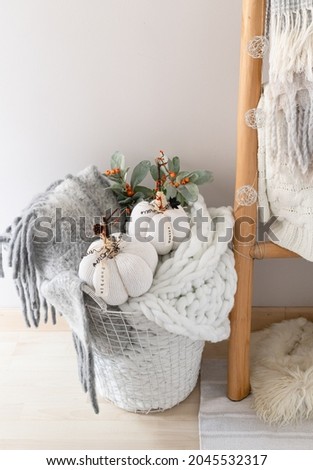 Handemade cozy white sweater  pumpkins and woolen blankets placed in  basket for autumn decoration. White knitted background