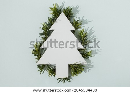 A silhouette of a Christmas tree made of fir tree branches on a white background. Minimalist Christmas concept. Modern winter festive pattern. Trendy Christmas layout. Copy space. Flat lay.