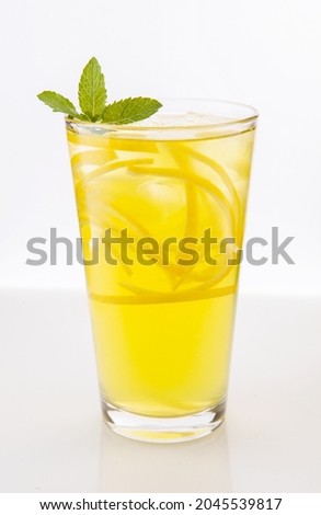 Lemonade iced yellow with soda, lemon slices, syrup, with ice cubes, decorated with mint leaves in a glass on a light background