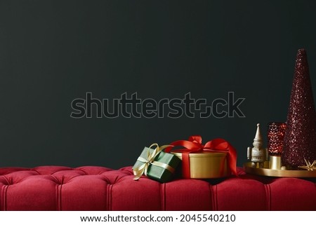 Christmas composition on the red velvet bench with decoration, gifts, wreath, lantern and accessories. Copy space. Red and green color. Template. 