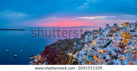 Famous greek iconic selfie spot tourist destination Oia village with traditional white houses and windmills in Santorini island in the evening blue hour, Greece Royalty-Free Stock Photo #2045551109