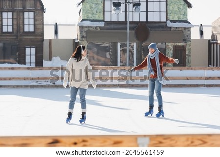 full length of joyful couple skating on ice rink outside